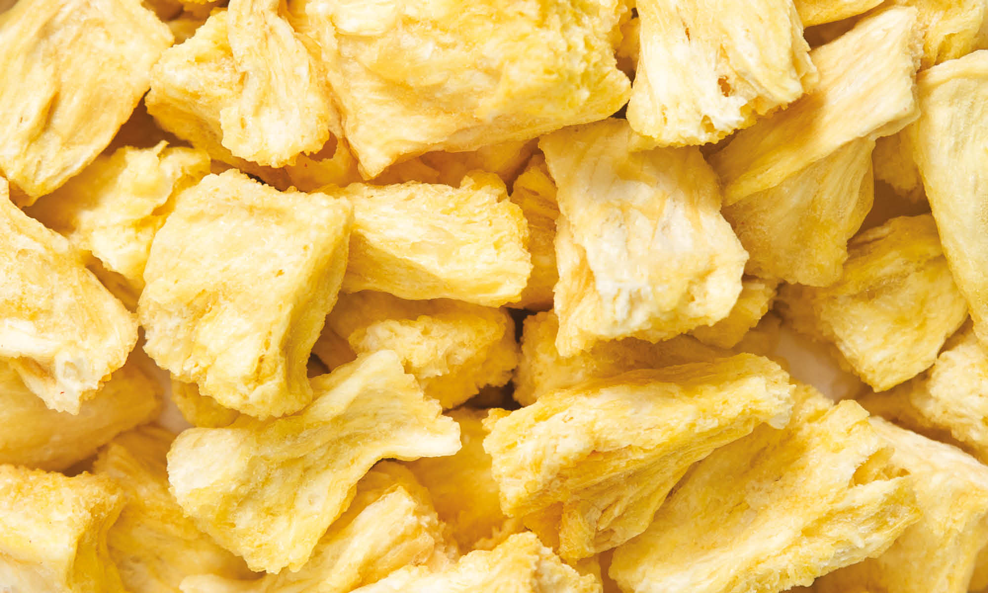 Viele, gelbe gefriergetrocknete Ananas Stuecke von buah liegen auf und nebeneinander