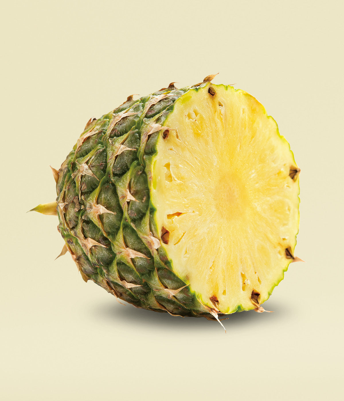 Frische, gelbe, aufgeschnittene Ananas Frucht vor gelbem Hintergrund