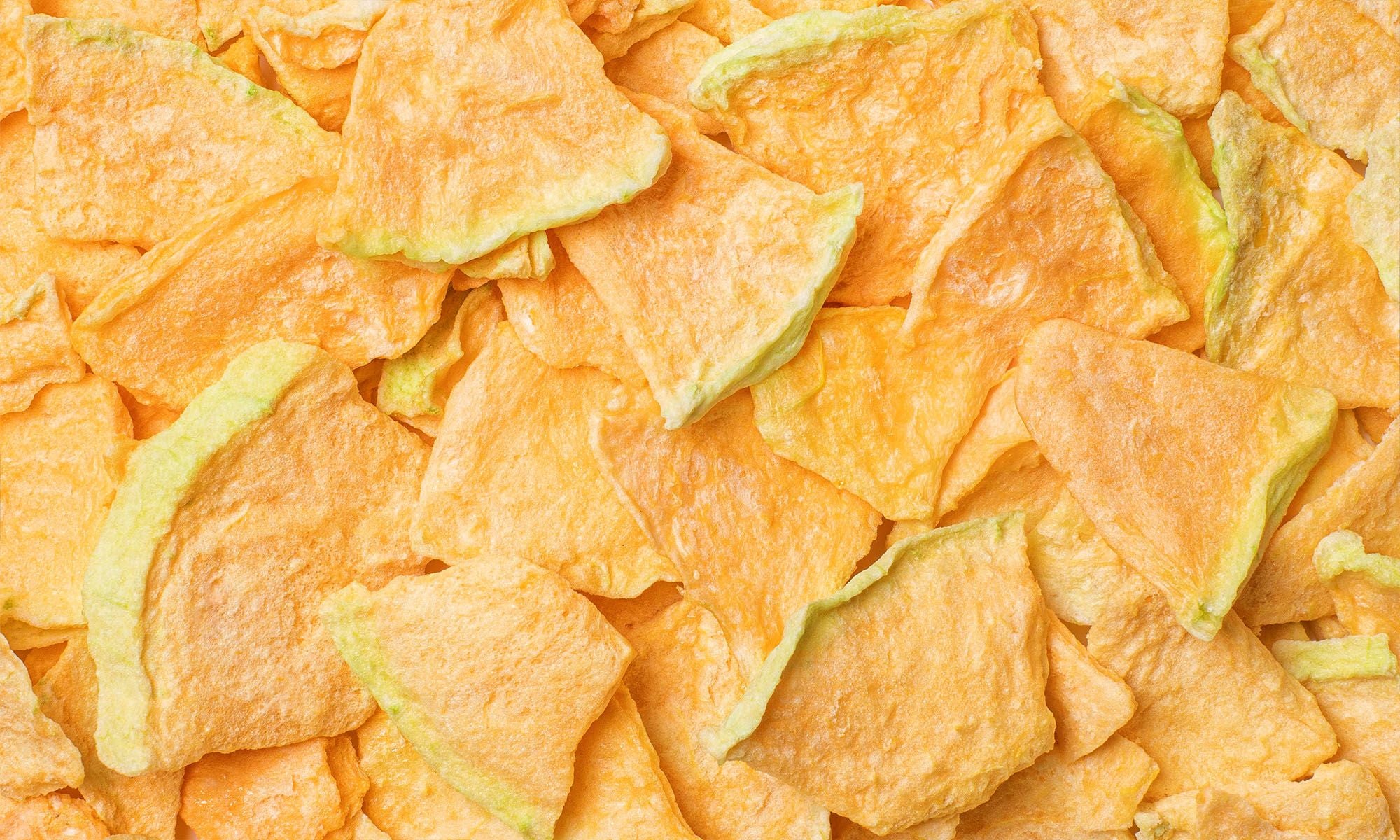 Viele grosse Stuecke Gefriergetrocknete Cantaloupe Melone von buah liegen auf und nebeneinander in satter oranger Farbe.