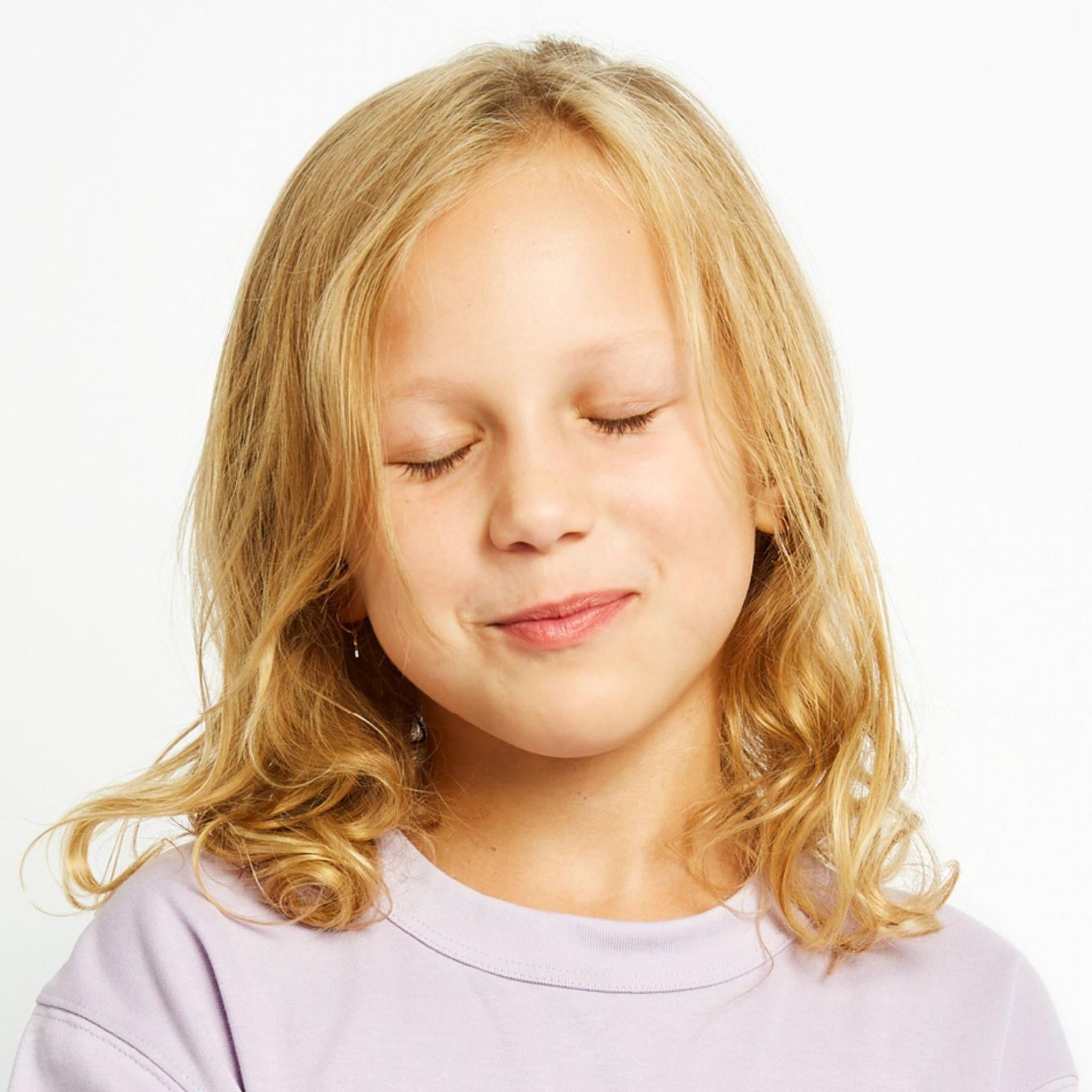 Maedchen mit geschlossenen Augen, blonden Haaren in einem lila T-shirt