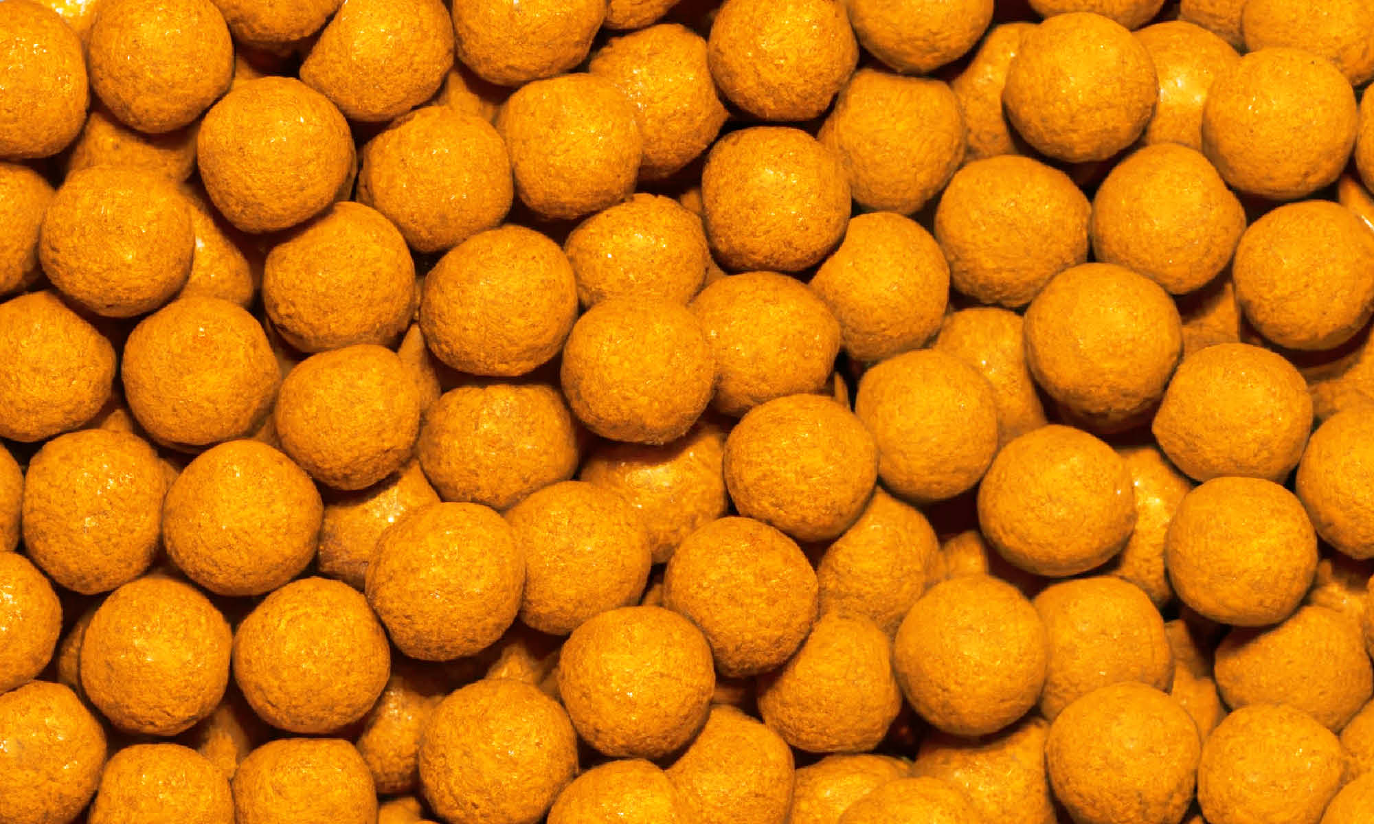 Viele kleine runde und orangene buah Mango-Maracuja Kaubonbons liegen auf und nebeneinander