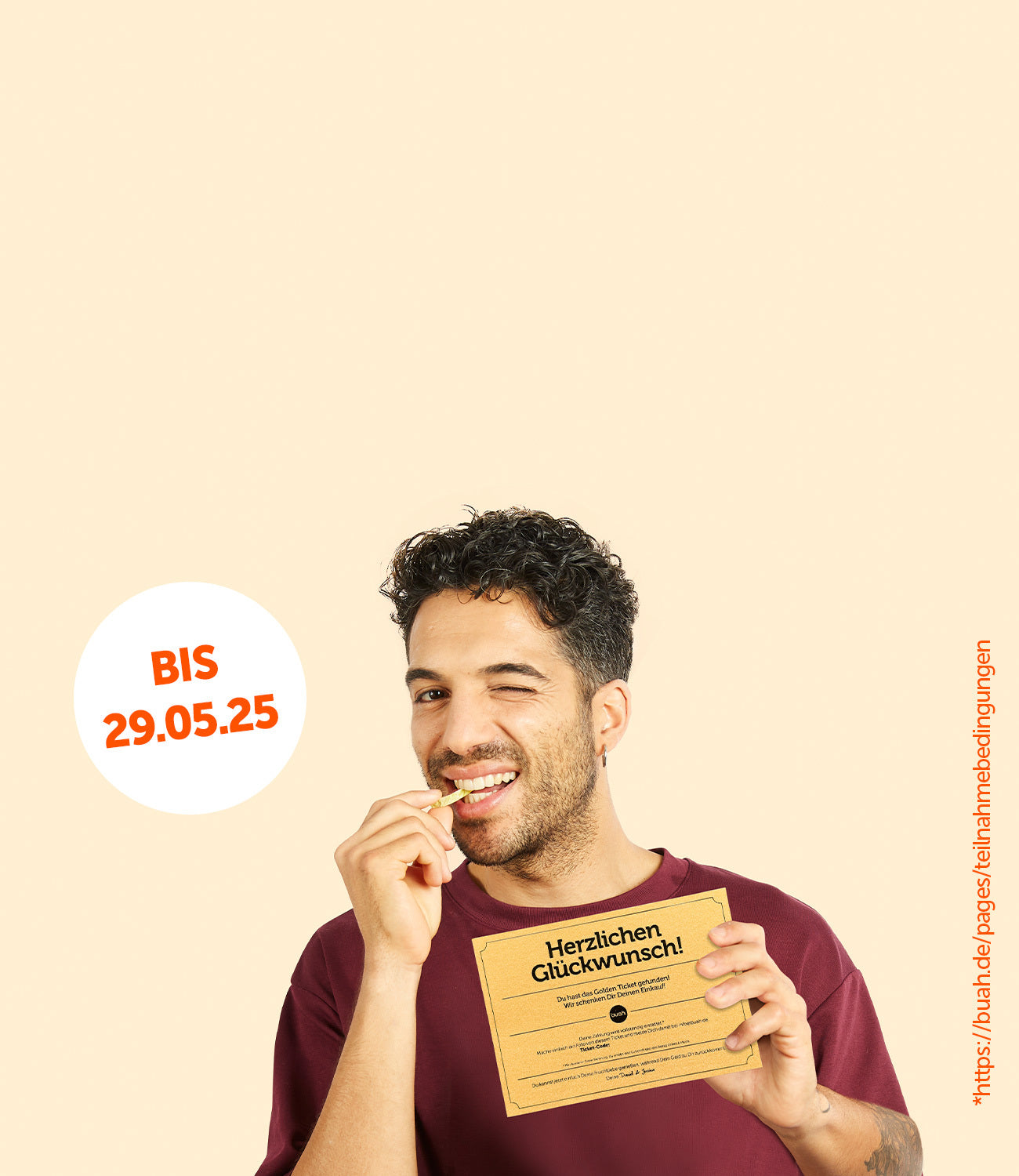 Junger Mann mit dunkelrotem Shirt hält ein Goldenes Ticket von buah in der Hand und grinst in die Kamera