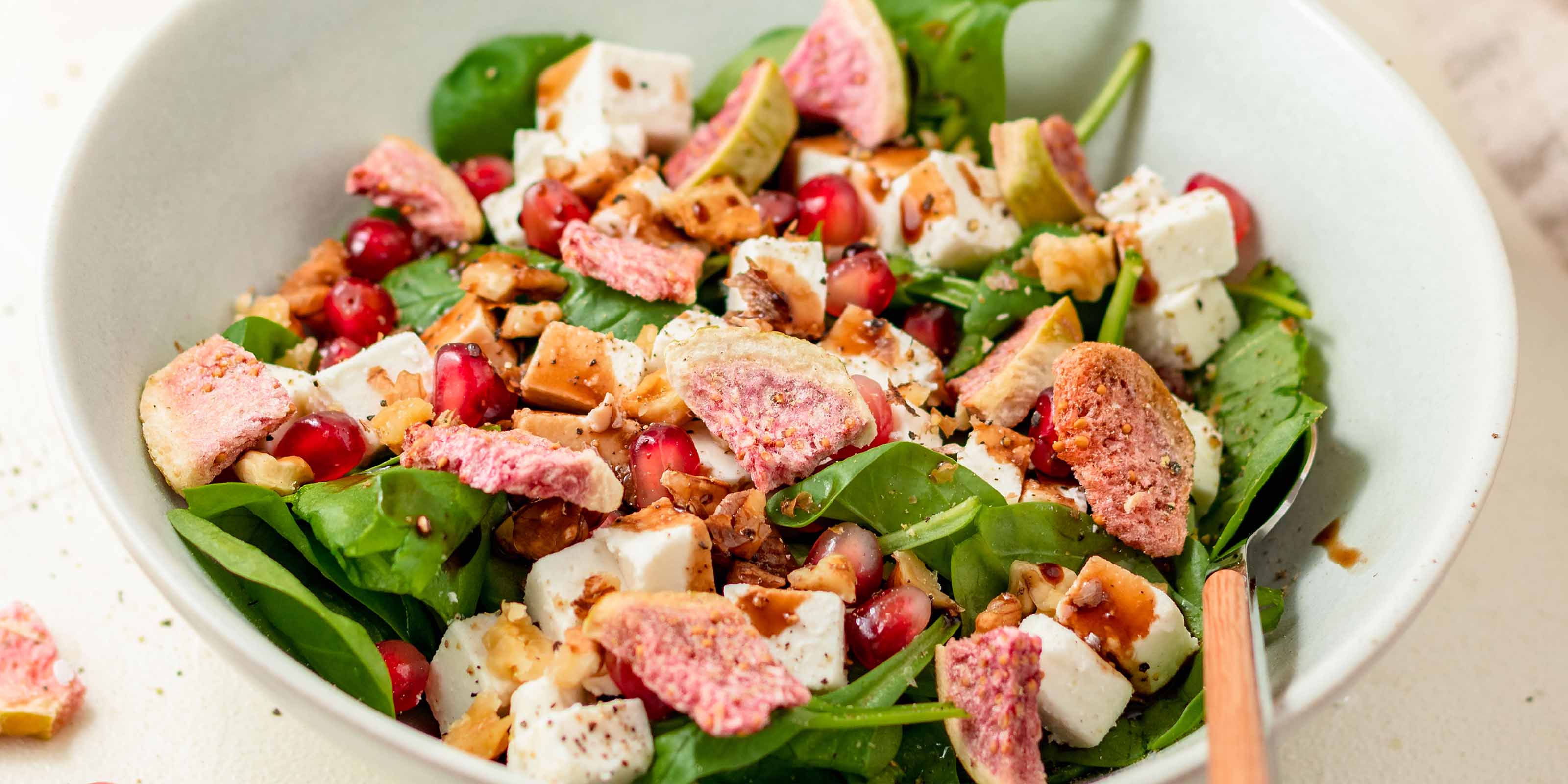 Salat in einer Schuessel mit Granatapfel, Nuessen und buah Feigen