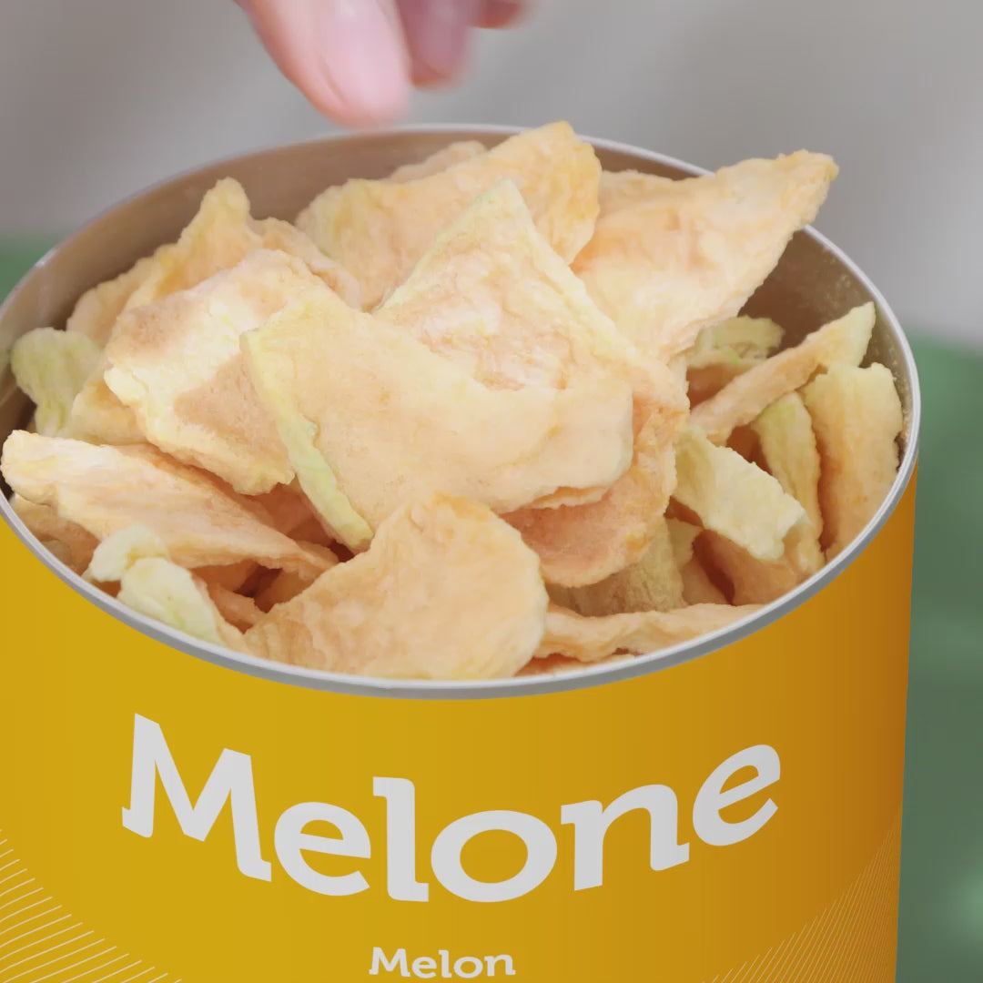 Video einer Junge Frau mit orangenem Shirt sitzt an kleinem Tisch und geniesst buah gefriergetrocknete Melone aus der Dose und gibt Melone auf Ihren Salat. 